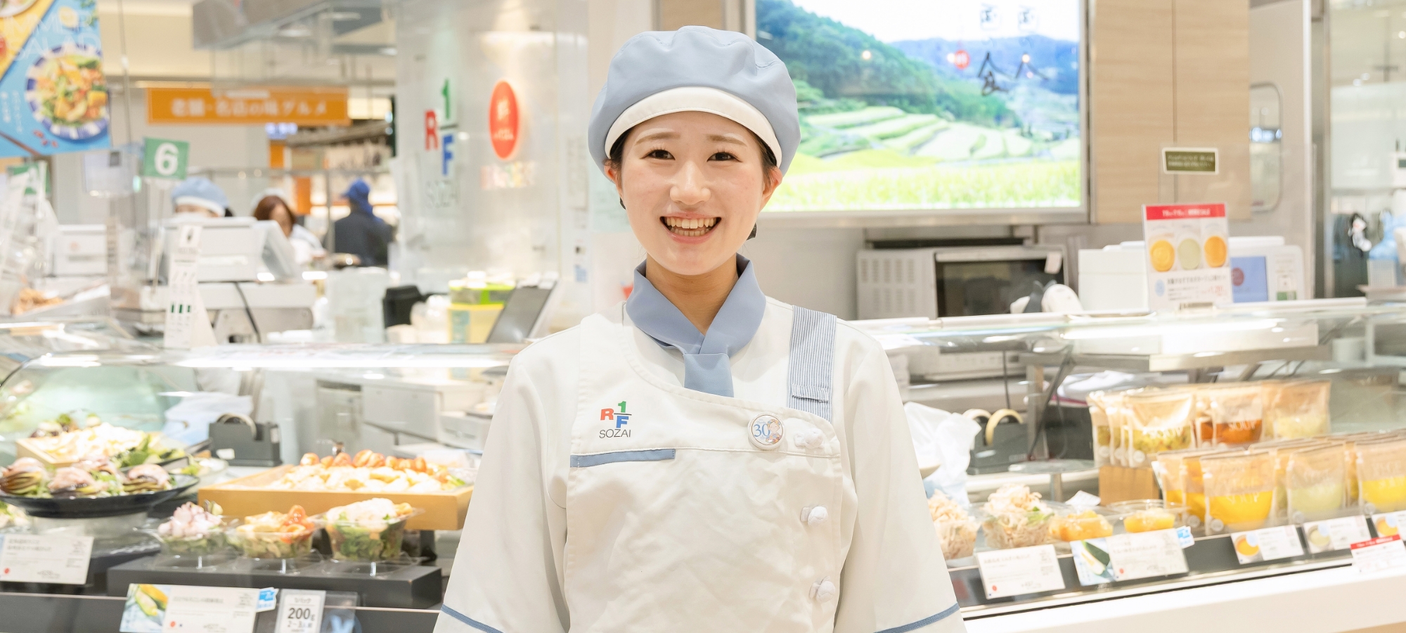 RF1の店舗前で正面向き笑顔で立っている学生スタッフの写真